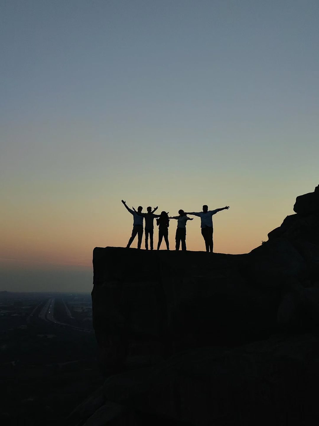 Group silhouette on a cliff at sunset