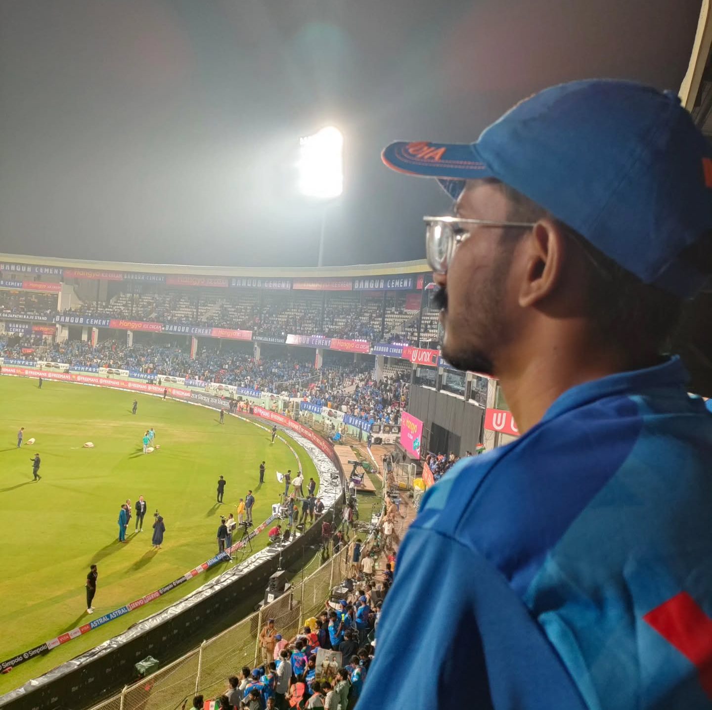 Fan watching the floodlit ground from the stands